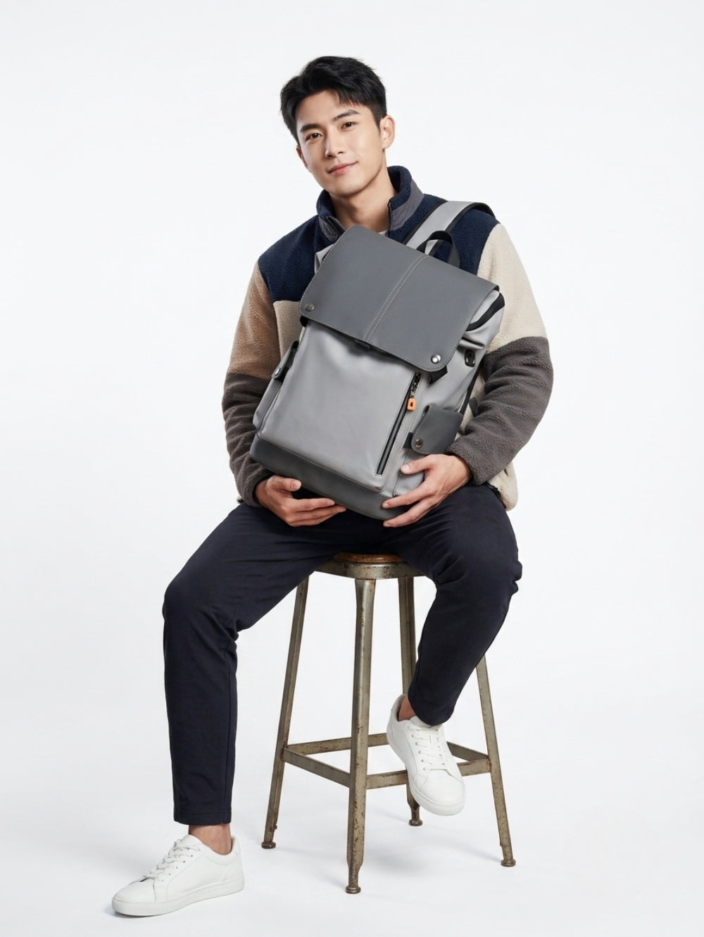 Grey Japanese style tooling backpack placed on a hand and set on a wooden chair