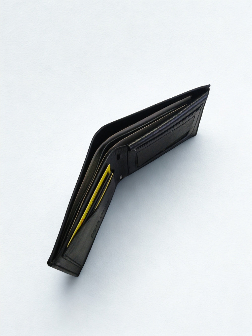 Top perspective view of open black leather bi-fold wallet displaying dual bill compartments