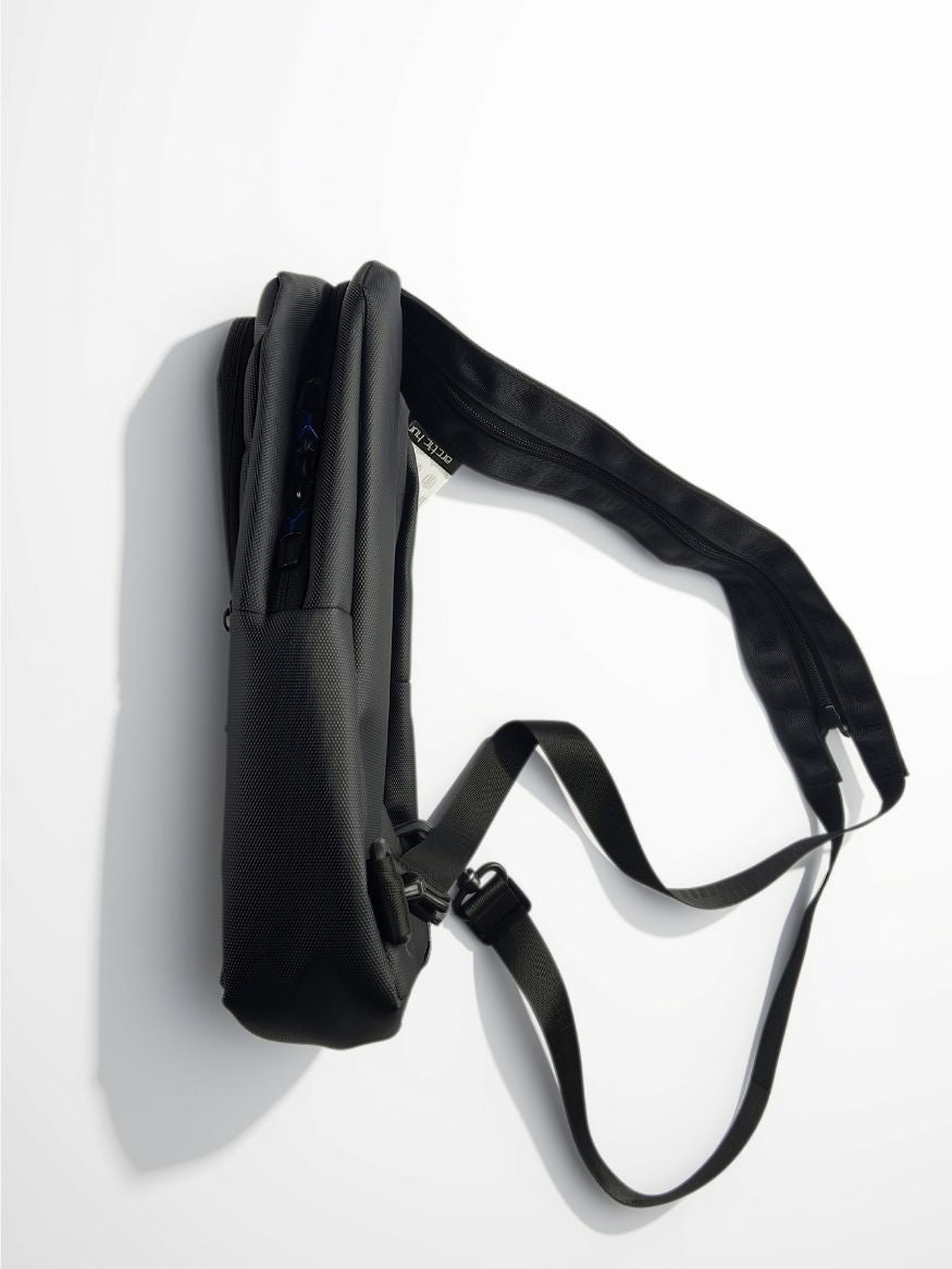 Side view of Arctic Hunter black crossbody sling bag showing slim profile and zipper compartments