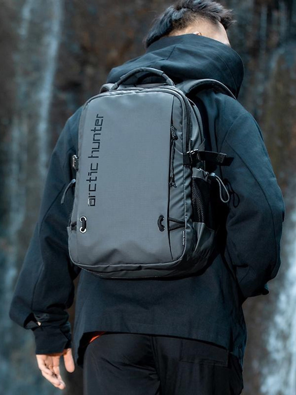 Male model wearing Arctic Hunter grey waterproof laptop backpack lifestyle outdoor view