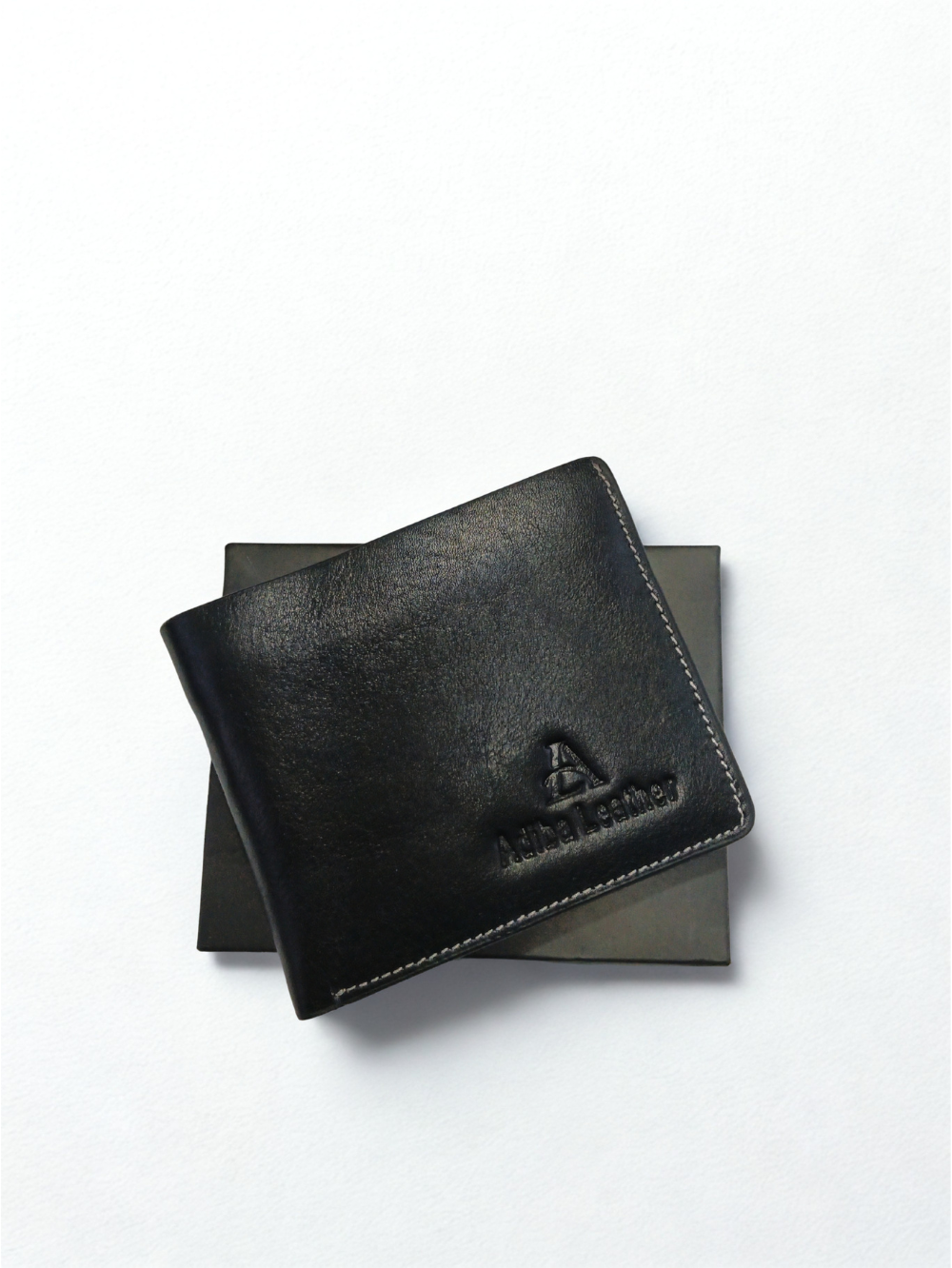 Black genuine leather bi-fold wallet resting on top of its presentation box lid