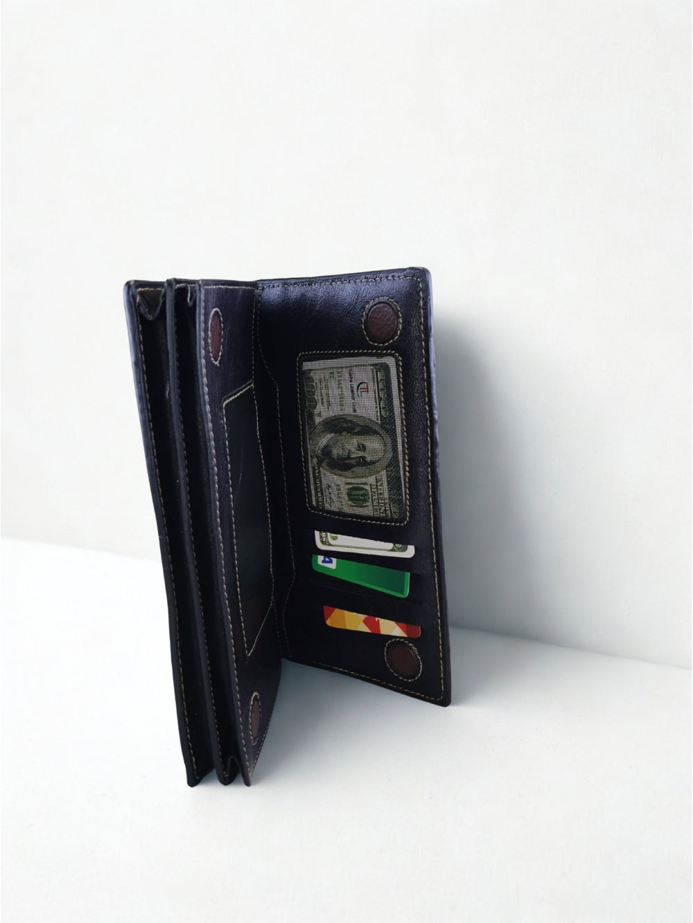 Side angle view of open black pebbled leather long wallet showing multi-layer compartments